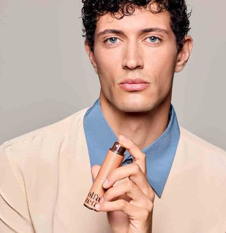 Mann mit dunkel lockigen haar hält das olfazeta taschen parfum etui vor sich und sprüht