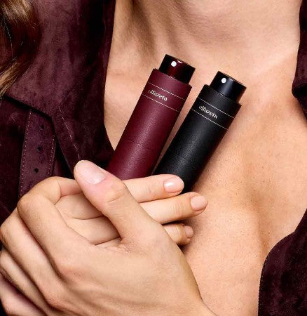 Frau hält olfazeta taschenparfums in Bordeaux und schwarz mit beiden hände auf die brust