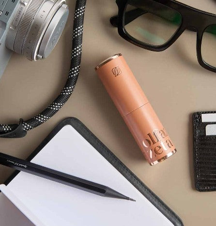 olfzeta parfum taschenetui liegt auf tisch mit sonnenbrille kamera und notiz block